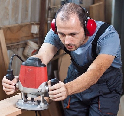 Man Using Wood Router wearing Ear Protection