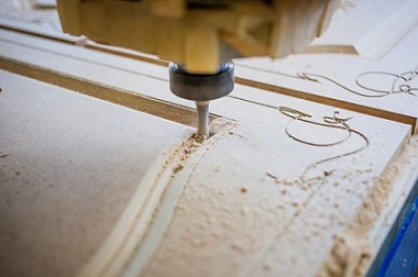 CNC router cutting out patterns on wooden door