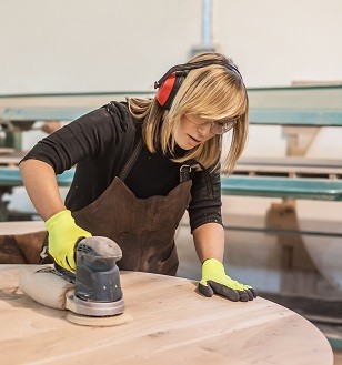 Lady sanding a table with electric sander
