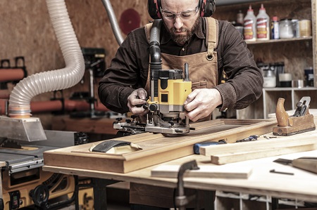 Man in work shop using wood router
